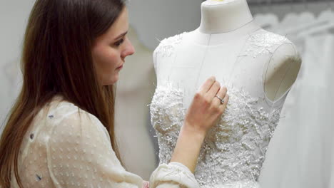 portrait of a girl creating a wedding dress by exclusive order sewing fabrics and rhinestones on a dress dressed in a mannequin. production of wedding dresses. little business