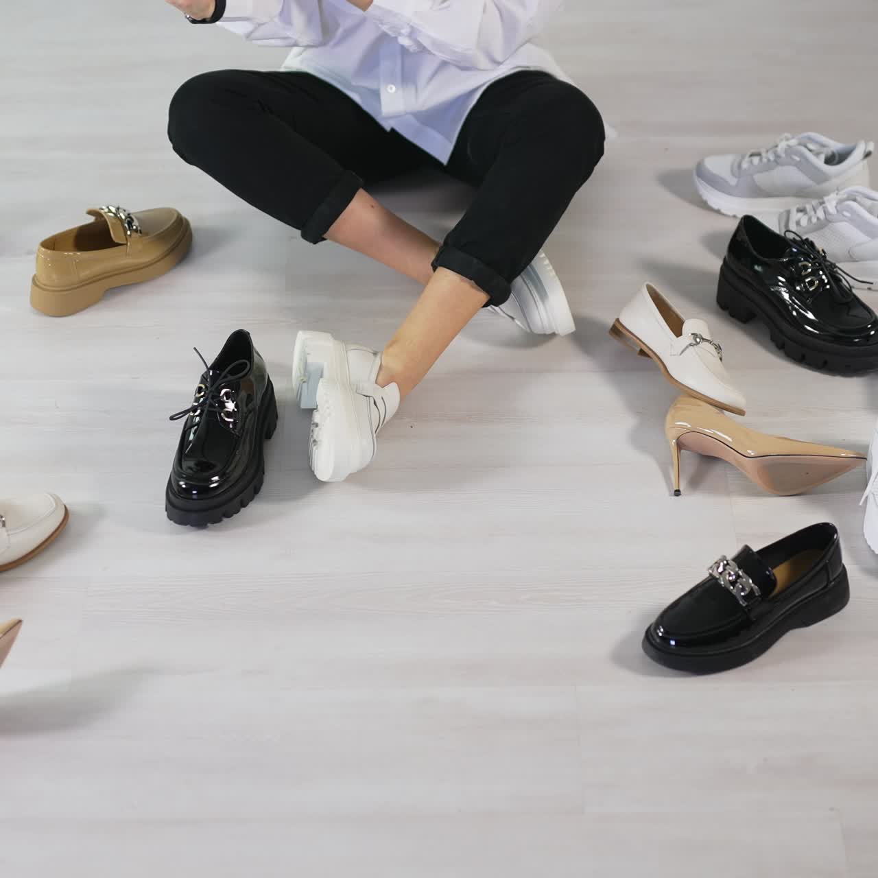 Lady looking over different kinds and styles of footwear. Hard choice decision of a new pair of shoes. Light floor backdrop