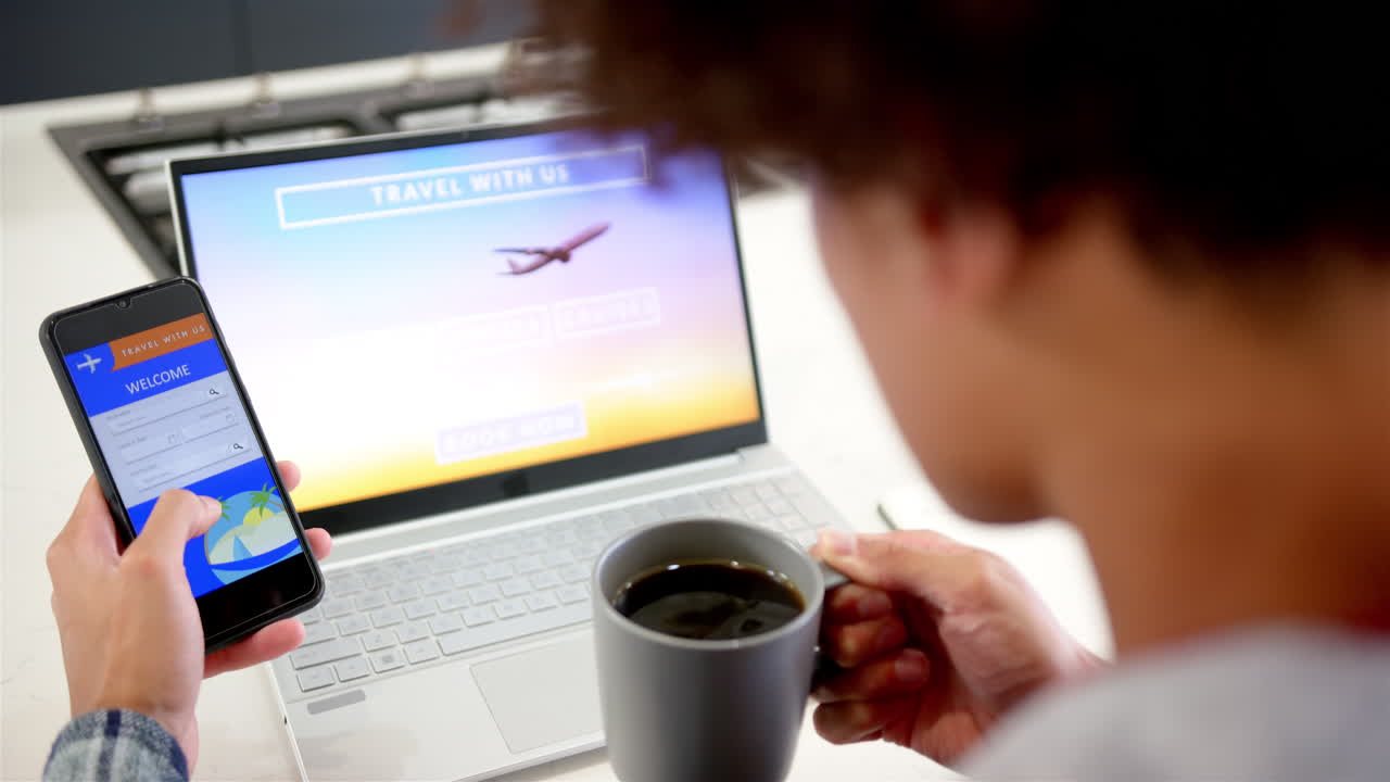 Booking travel online, man using smartphone and laptop while holding coffee cup