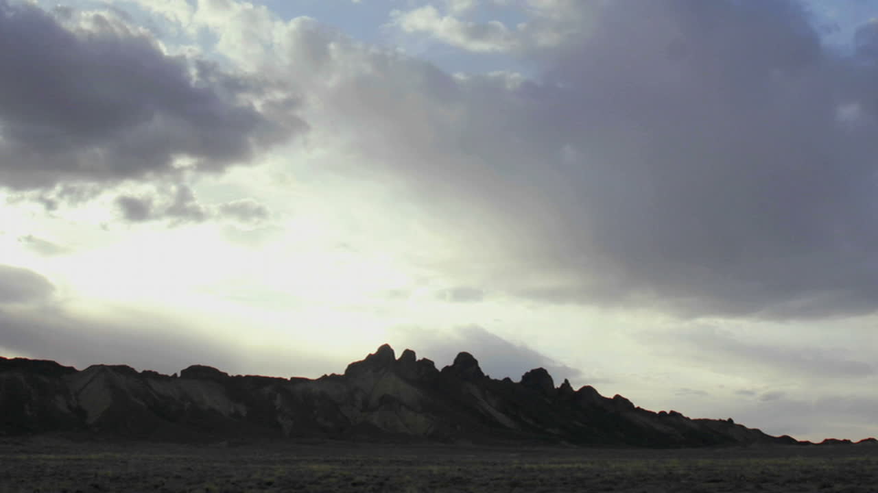 희미한 회색과 흰 구름이 황금시간대에 산 정상을 지나간다