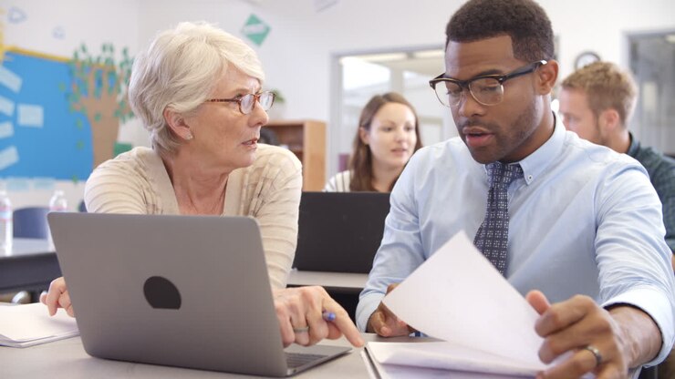 Teacher and student using laptop at an adult education class