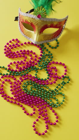 video vertical de máscara de mascarada y cuentas de carnaval de mardi gras en fondo amarillo