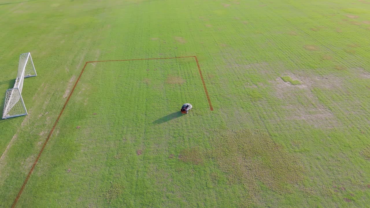 A robot autonomously paints precise lines on a soccer field, showcasing advanced automation technology in a sunny outdoor setting