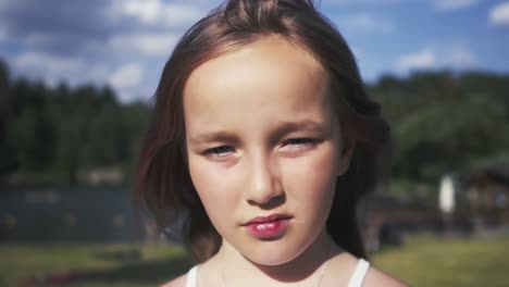 Portrait-of-an-eight-year-old-girl-squinting-her-eyes-on-a-bright-summer-day