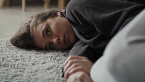 Caucasian-woman-lying-down-at-the-carpet-in-home-with-mental-problem.