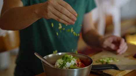 man adds chopped green onion to a salad, filmed in slow motion