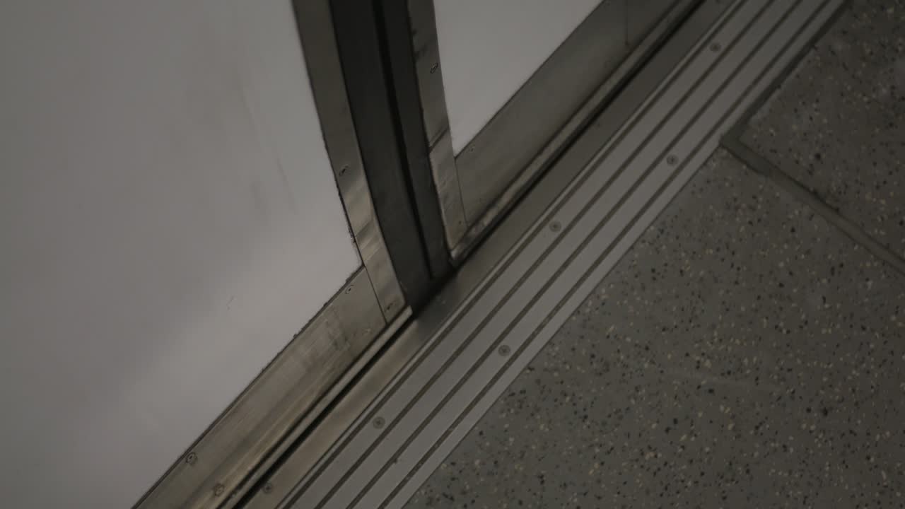 Vista interior con enfoque selectivo de las puertas de un vagón de metro de cercanías abriéndose en un andén vacío.