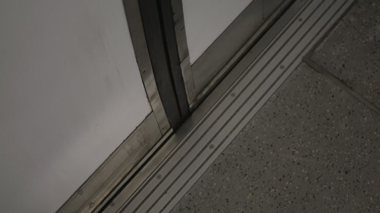 Uma visão interior com foco selecionado nas portas de um metrô abrindo, mostrando as portas de um carro de metrô de passageiros enquanto se abrem em uma plataforma vazia.