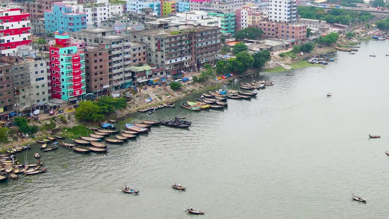 A high-angle shot of small boats on the Buriganga River by Dhaka's bustling riverfront