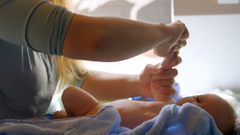 mother giving hand massage to her baby boy at home 4k