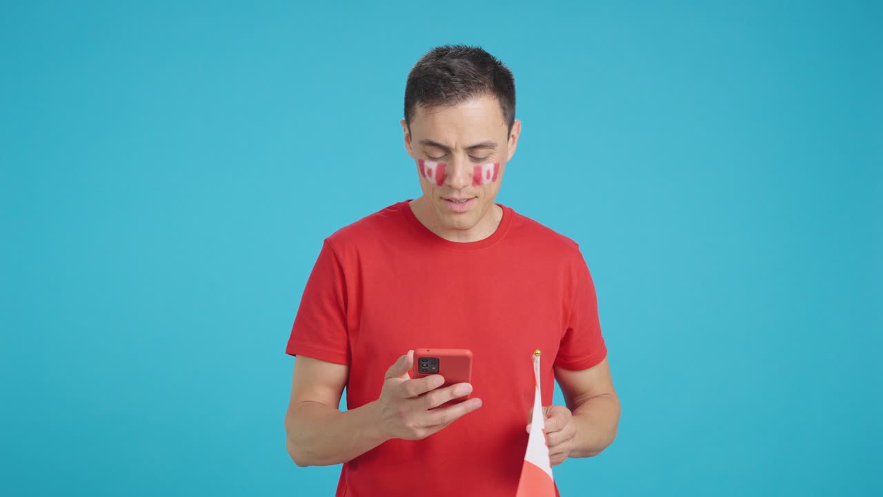 Canadian supporter looking at his mobile smiling and showing it