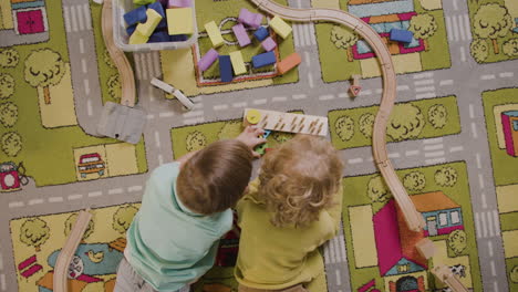 bovenaanzicht van spelende kinderen met houten stukken liggend op een tapijt in een montessorischoolklas