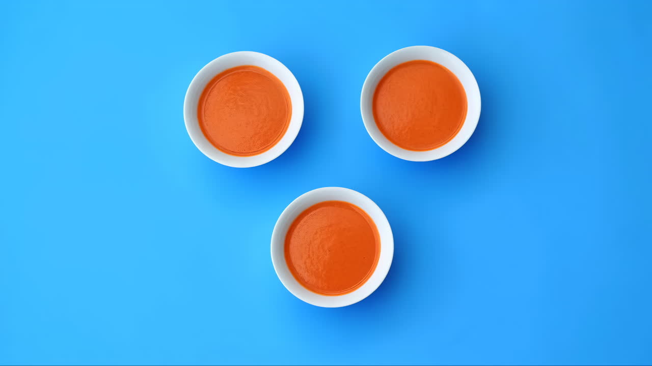 Three Bowls of Orange Soup on a Blue Background