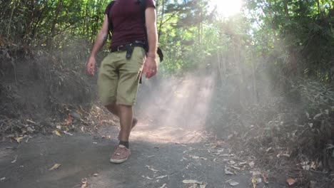 una pareja caminando por un sendero polvoriento en un bosque iluminado por el sol en el monte batur, bali, indonesia