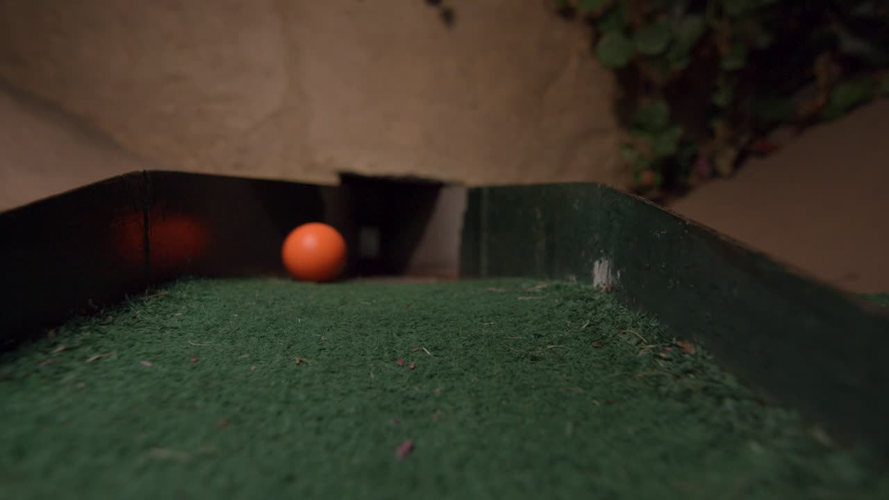 An orange mini golf ball going into the last section of the course