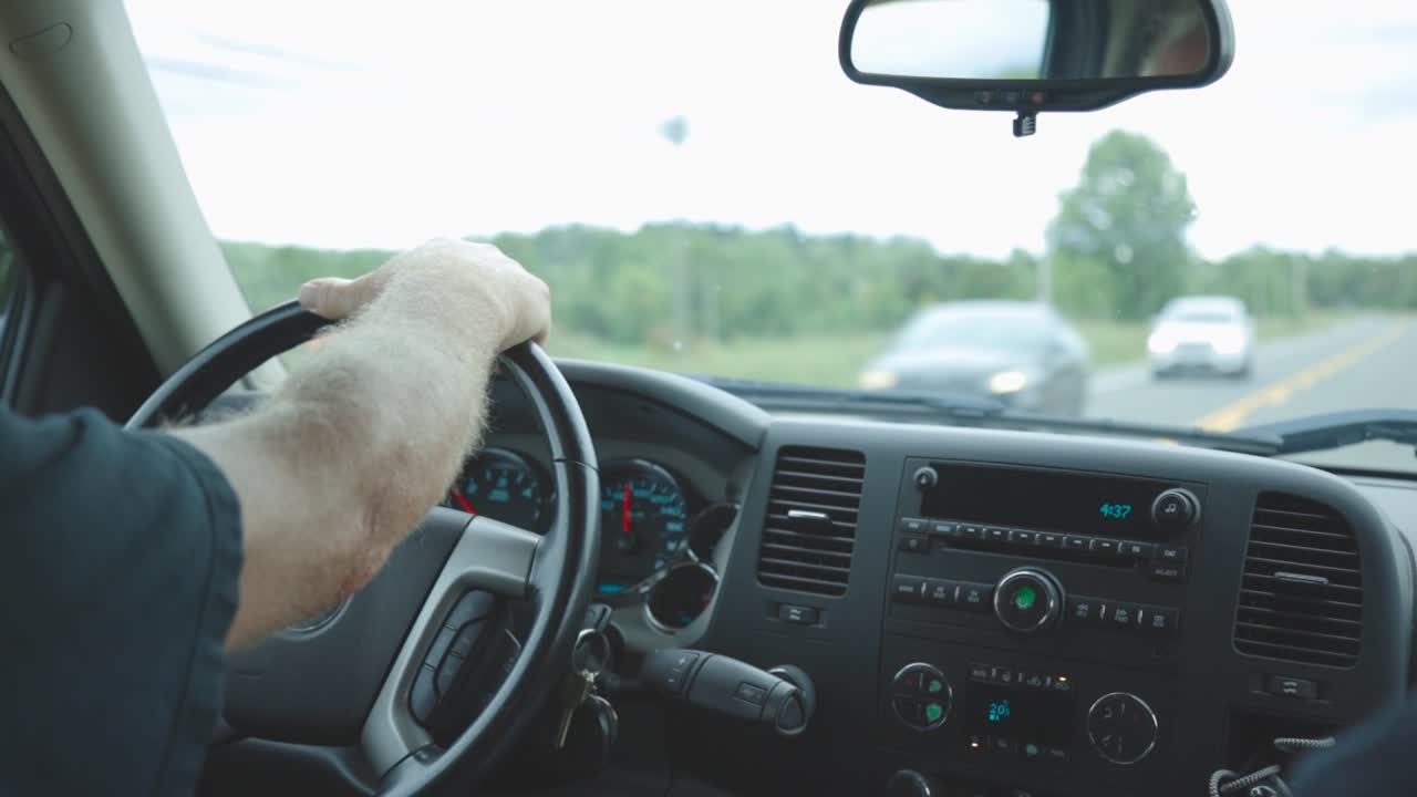 Driver Driving A Car On The Asphalt Road, Hand On The Steering Wheel - extreme close up