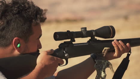 close-up of a hunter aiming through a scope for a target and shooting