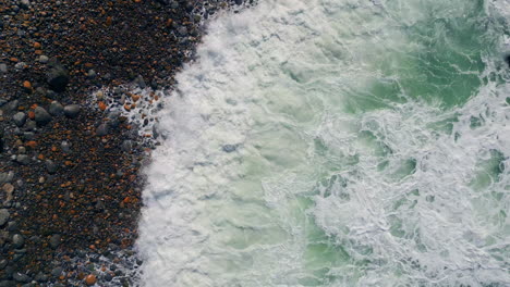 ocean foam rolling stony beach drone view. stormy rough waves foaming seashore