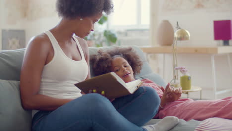 Relaxed-mother-and-daughter-reading-and-talking,-staying-in-bed