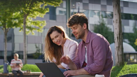 managers working laptop street together. smiling freelancers discussing project