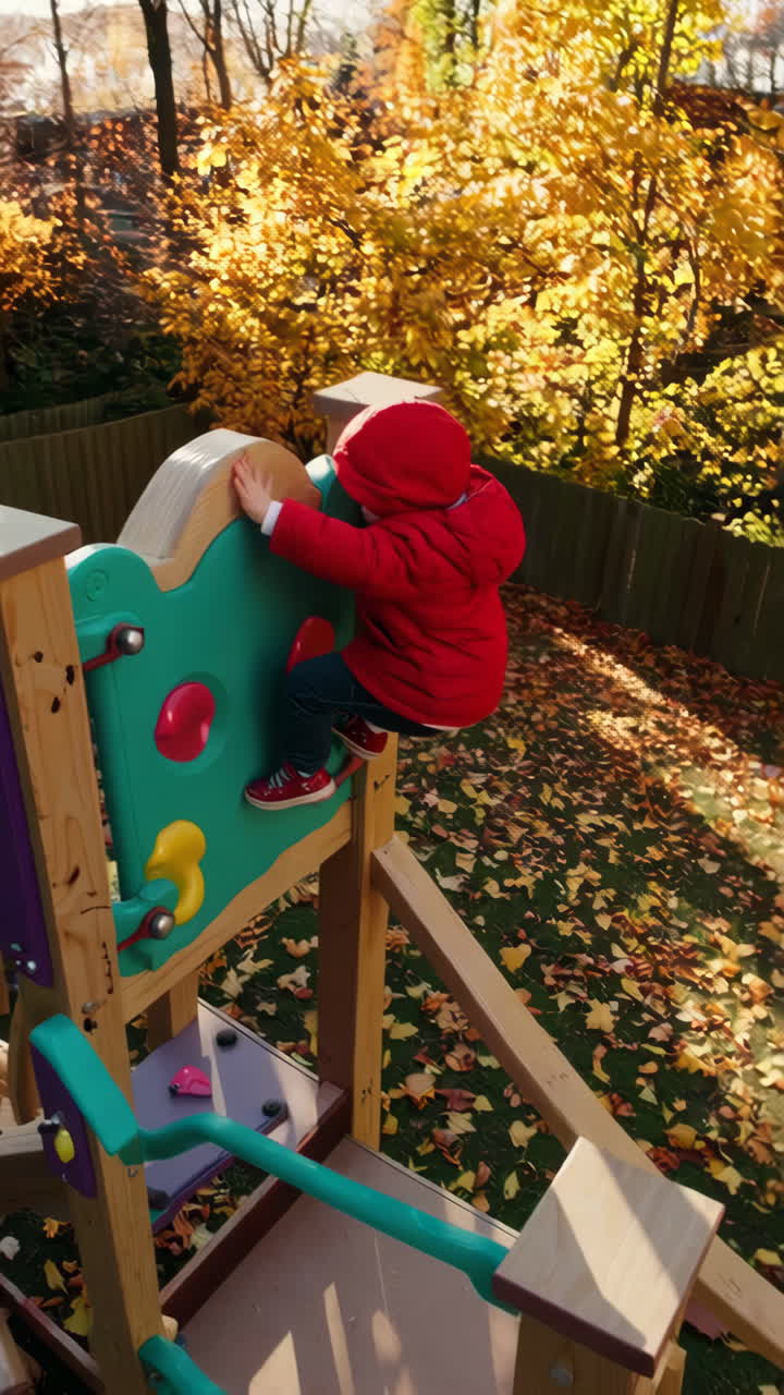 Niño pequeño jugando en un parque infantil entre hojas de otoño