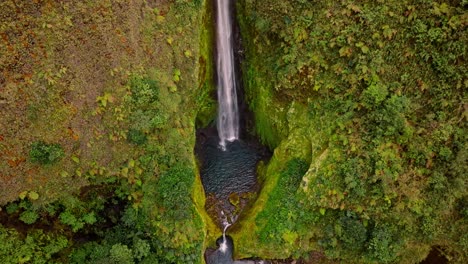an breathtaking aerial view reveals the unique and beautiful vuelta al cañon waterfall, cascading majestically into a vibrant, untouched green canyon