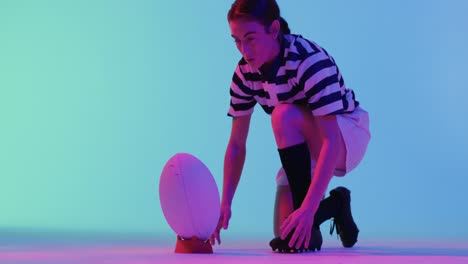 caucasian female rugby player with rugby ball over neon pink lighting