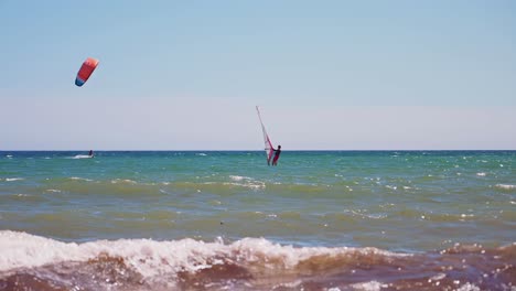 Windsurfing-with-a-clear-sky-and-a-kite-surfer-passing-by-on-the-background