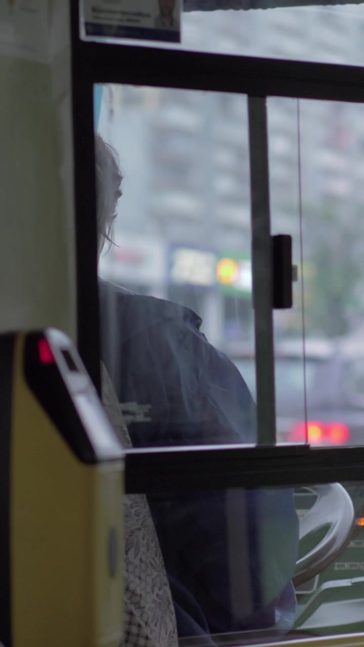 View to bus cabin with female driver and road traffic