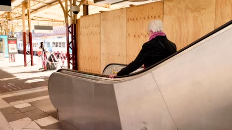 elderly woman rides escalator at melbourne station