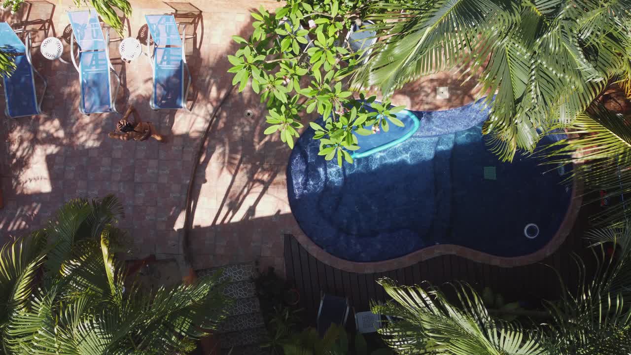 vista aérea: mujer latina sale de la piscina del complejo para relajarse en la silla de estar