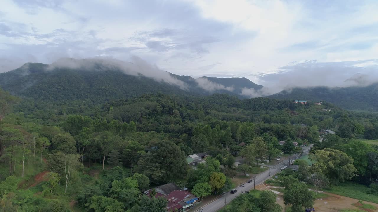 Ascending drone shot of green lush mountains with clouds on top