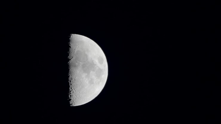 Uma imagem da lua quarto crescente subindo lentamente no céu em Tóquio, Japão.