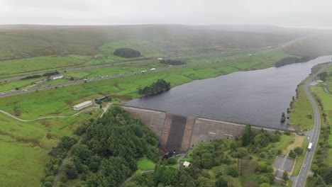 Vista-Aérea-Del-Depósito-De-Madera-De-Stand-Volando-Sobre-La-Barrera-Del-Lago-Hacia-La-Autopista-M62-En-El-Campo-De-West-Yorkshire