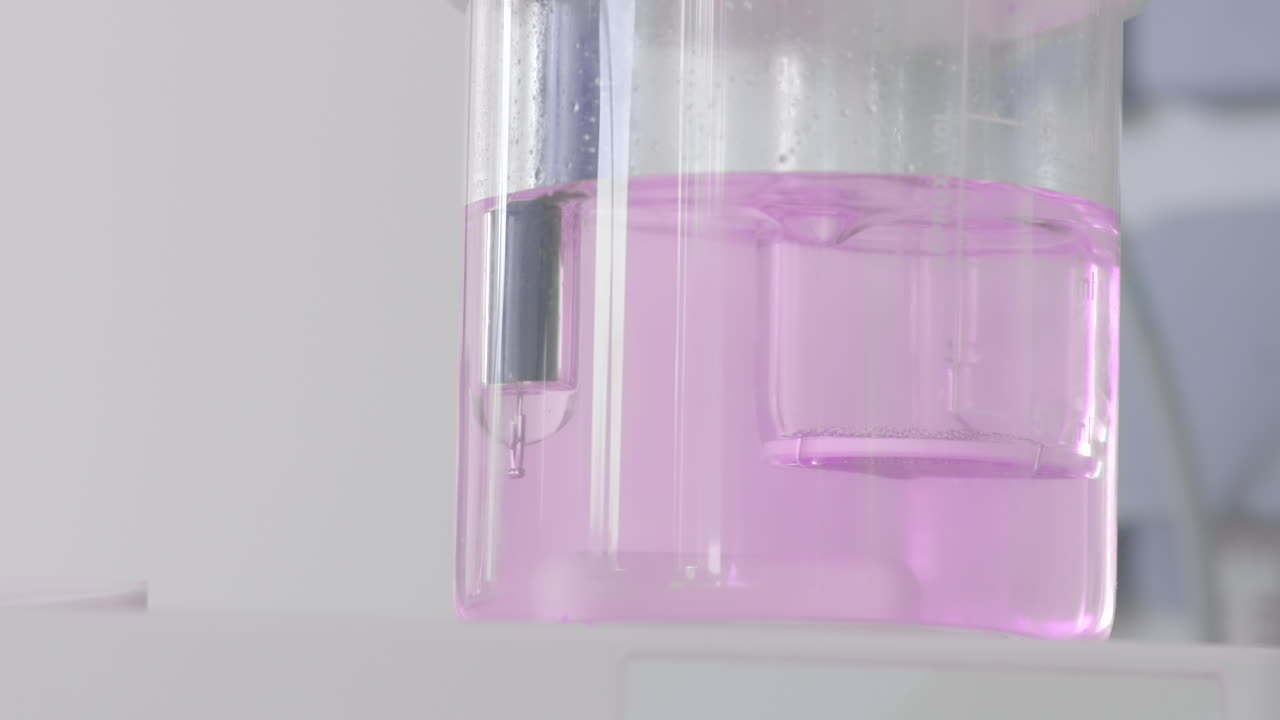 Liquido rosa in becher da laboratorio