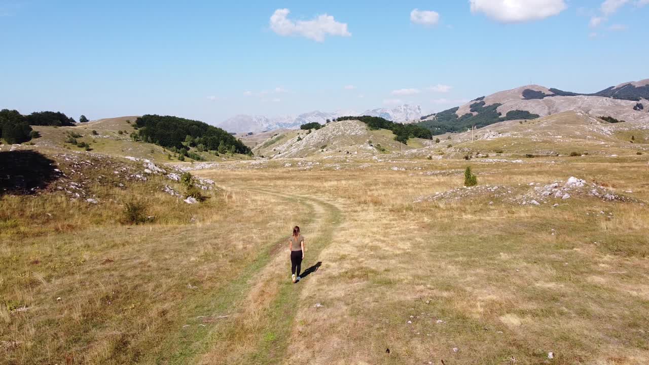 mujer camina en el parque nacional de durmitor, montenegro - carretilla aérea hacia adelante