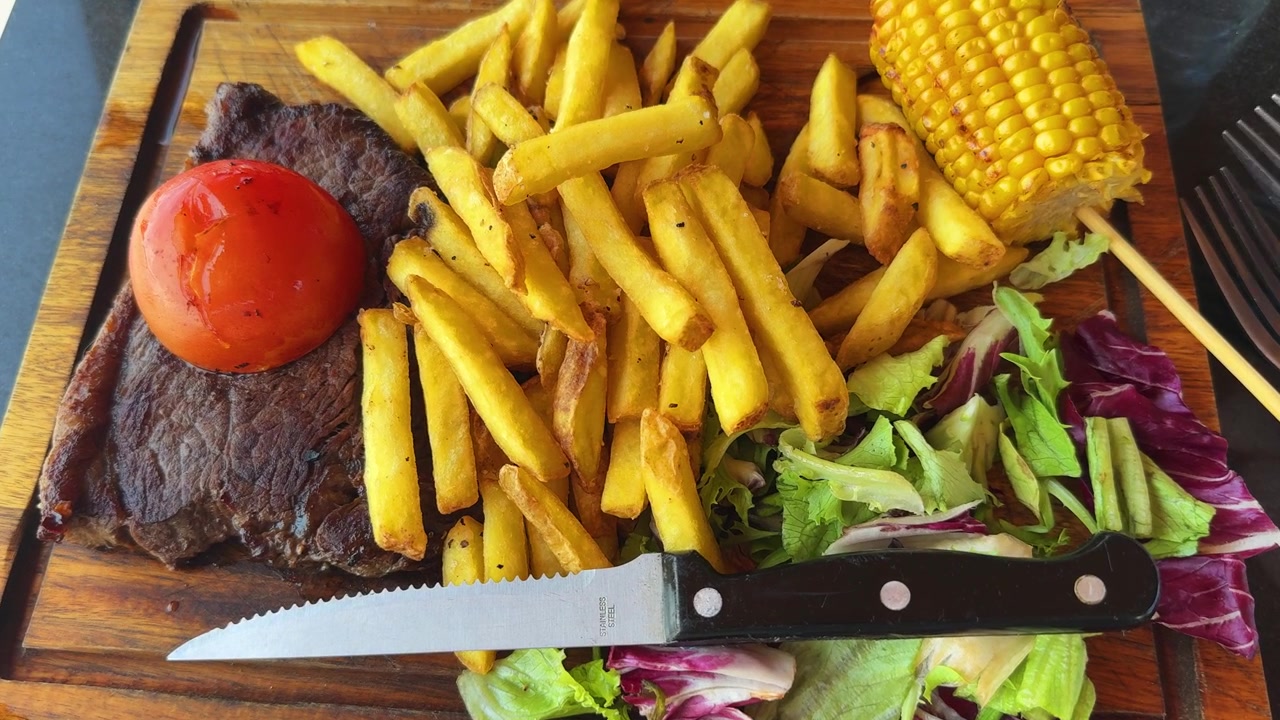 Bistecca, steakhouse, cena a base di manzo, ristorante costoso, insalata di mais, patatine fritte.