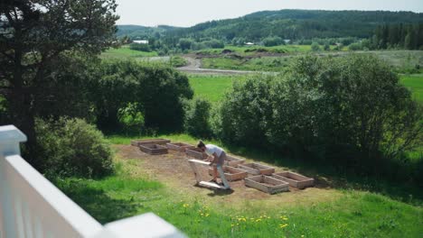 Person-Arranging-Wooden-Garden-Raised-Bed-At-The-Yard