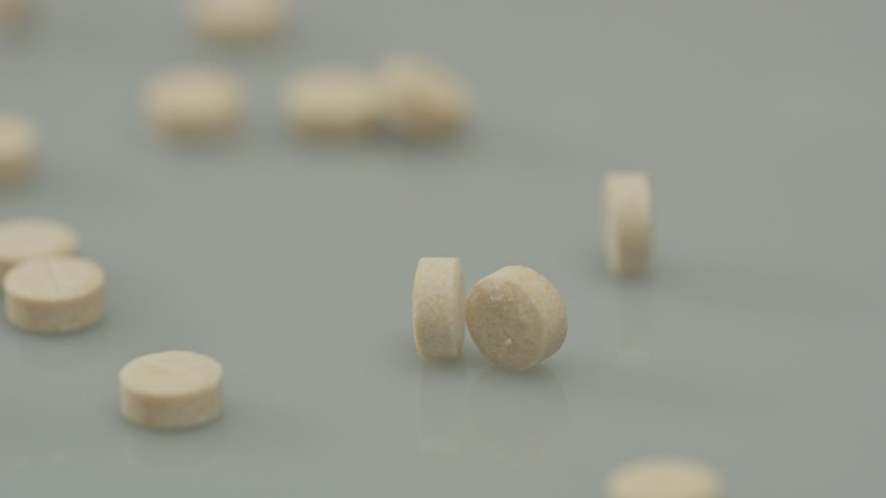 Panning over several pills scattered around a white surface
