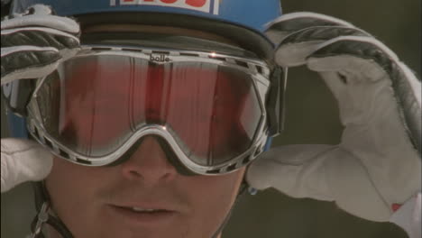 a skier adjusts his goggles