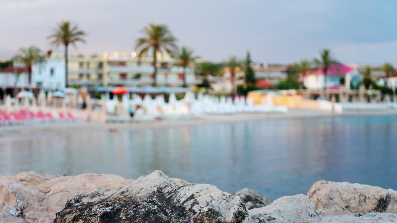 Close up of rugged white rocks with a blurred view of the beach in Cannes, France in the evening