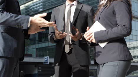 business people with digital devices talking on street