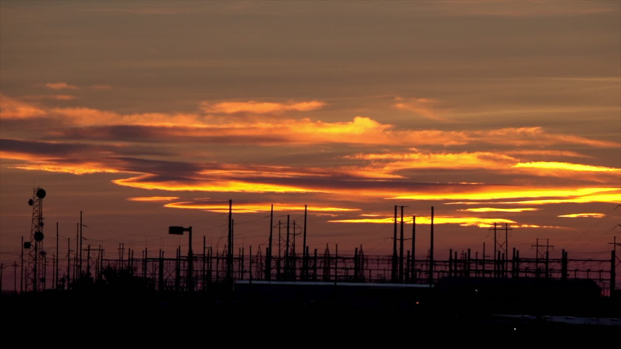 Electrical station and other infrastructure silhouetted against a sunset.