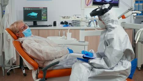 una mujer con un traje de protección midiendo la temperatura de una anciana.