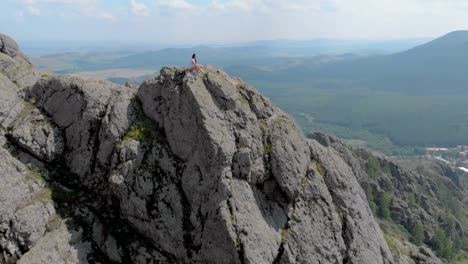 a young woman is sitting on the edge of an impressive mountains mountain cliff, dolly zoom effect