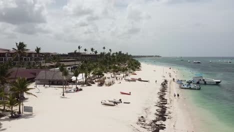 Drone-flight-on-beaches-of-punta-cana-dominican-republic,-with-some-boats-standing-on-the-shore,-sunny-weather-and-clear-blue-sky