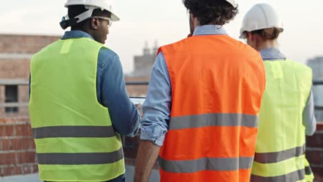 Vista-Posterior-De-La-Gente-Multiétnica-Con-Cascos-Caminando-Y-Hablando-En-El-Sitio-De-Construcción.-Constructores-En-La-Obra.-Al-Aire-Libre.-Trasero.