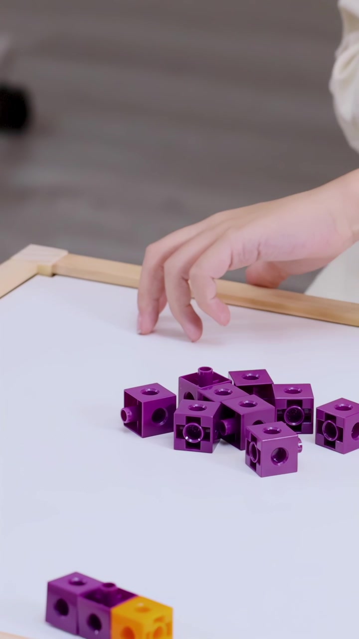 Mani di una persona che collegano mattoncini da costruzione viola e arancioni
