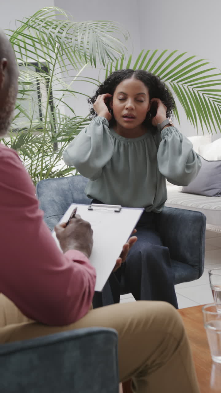 Vídeo vertical de terapeuta masculino diverso e paciente feminina conversando durante a terapia, em câmera lenta