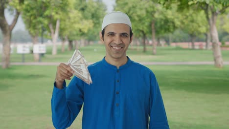 egoistic muslim man using money as fan in park